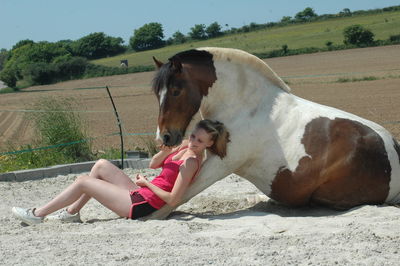 Woman and pony sitting on field