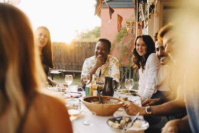 Cheerful friends talking while enjoying dinner at dining table in party