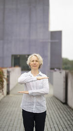 Portrait of woman with umbrella standing against building in city