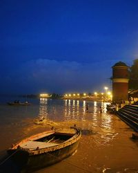 Boats moored on illuminated sea against sky at night