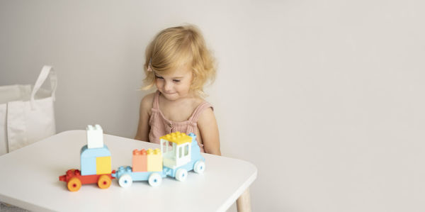Pretty caucasian 1,2 year old with blond curly hair playing with colourful construction, toys