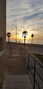 Footpath by sea against sky during sunset