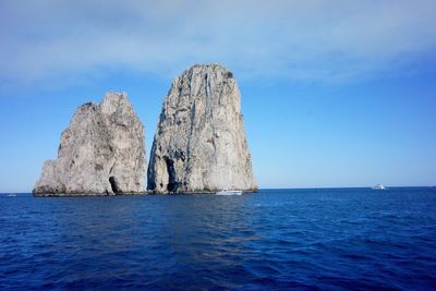 Idyllic shot of rock formation in sea against sky