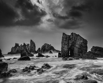 Rock formations on beach against sky