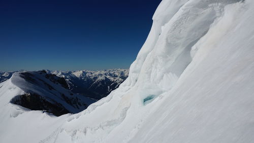 Scenic view of snowcapped mountains against clear blue sky