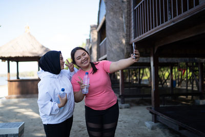 Portrait of smiling young woman standing against building