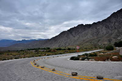 Man on road by mountains against sky