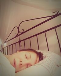 Close-up of young woman sleeping on bed at home