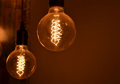 Close-up of light bulb hanging against black background