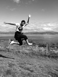 Full length of man jumping on field against sky