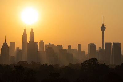 Modern buildings in city against sky during sunset