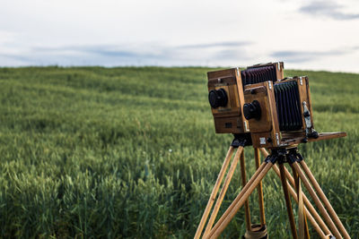 Close-up of cameras on field against sky