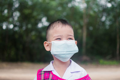 Boy wearing mask looking away standing outdoors