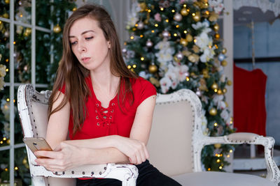 Girl with a phone on the background of a christmas tree. freelance work via phone.