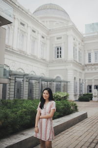 Portrait of woman standing against building