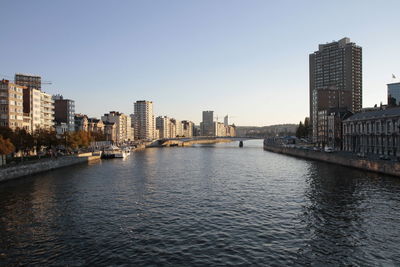 River amidst buildings in city against clear sky