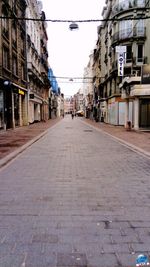 Empty footpath amidst buildings in city