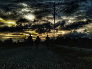 Silhouette people on field against sky during sunset