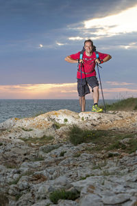 Portrait of young woman standing at sea shore against sky