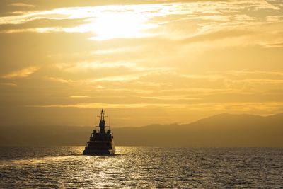 Silhouette of ship in sea during sunset