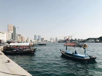 Boats in sea against clear sky in city