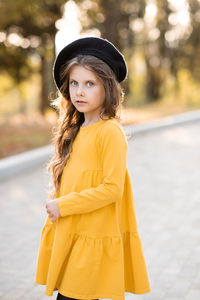 Stylish child girl 5-6 year old wear yellow dress and beret hat in autumn park outdoor.