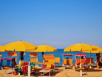 People at beach against clear blue sky