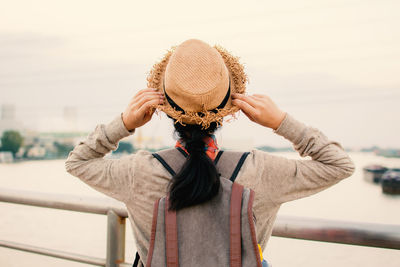 Rear view of man wearing hat standing against sky