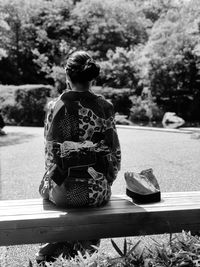 Rear view of woman sitting on rock