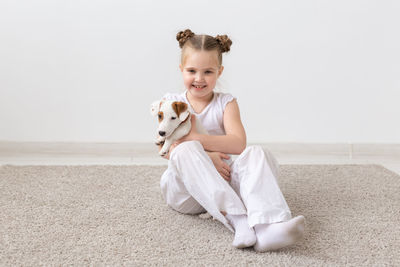 Portrait of smiling woman playing with puppy at home