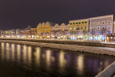 Illuminated city by water at night