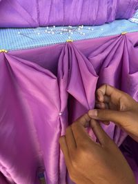 Close-up of hands making decoration with purple textile