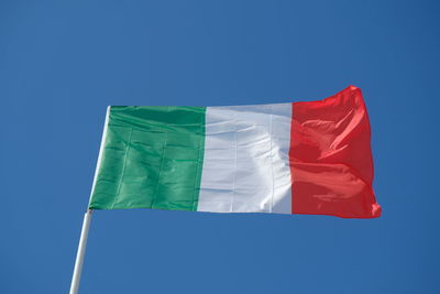 Low angle view of flag against blue sky