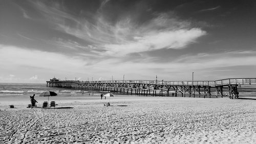 People on beach against cloudy sky