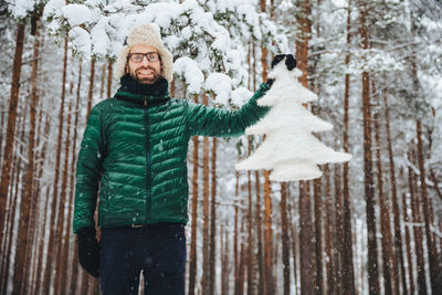 Portrait of man standing in snow covered forest