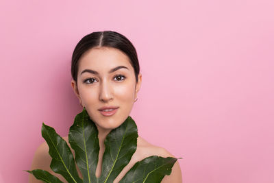 Portrait of young woman against pink background