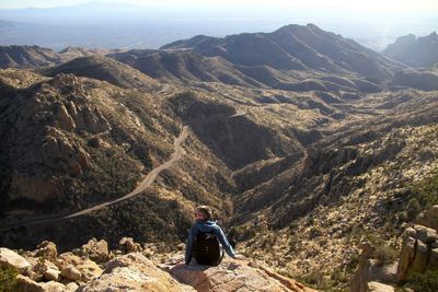 Man sitting on landscape against mountains