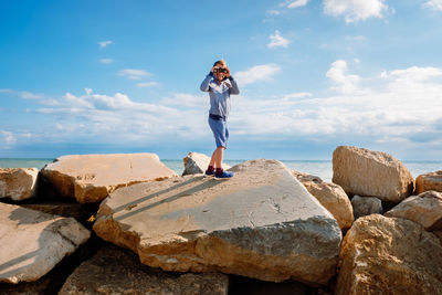 Rear view of man standing on rock against sky