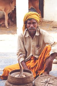 Charmer sitting by snake in basket