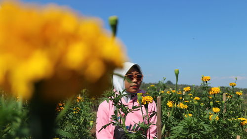 Woman standing on yellow flowering plants