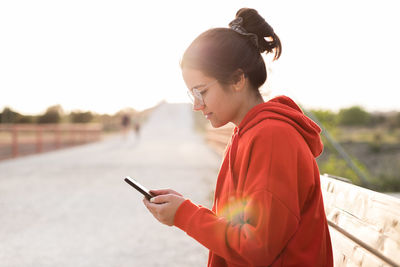 Side view of young woman using mobile phone