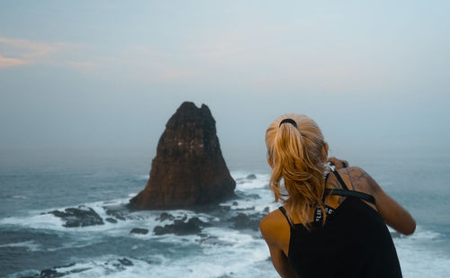 Rear view of woman looking at sea against sky