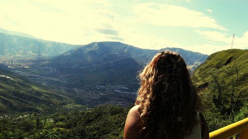 Rear view of woman looking at mountains against sky