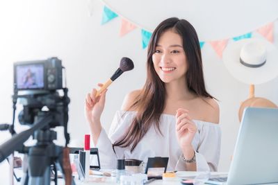 Portrait of smiling young woman holding smart phone on table