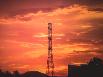 Low angle view of silhouette communications tower against orange sky