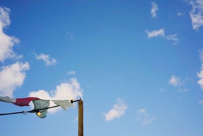 Low angle view of white flags against blue sky