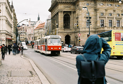 Rear view of man standing against tram on city street