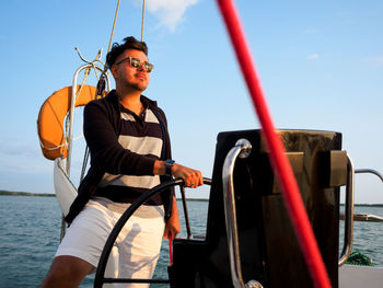 Handsome person steering wheel sailing yacht or sailboat on a vacations