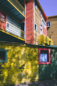 Low angle view of multi colored house by building against sky