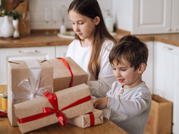 Brother and sister wrapping gift at home